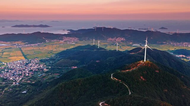 Wind turbines on coastal mountain ridges at sunset. Clean energy concept.