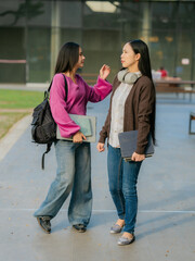 Fototapeta premium Two Asian women with active lifestyles are seen walking to work, chatting together on their way to the office.