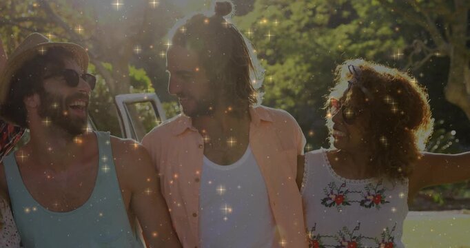 Four friends walking, fourth joining and wrapping arm, sparkles overlay promoting sunlit travel van