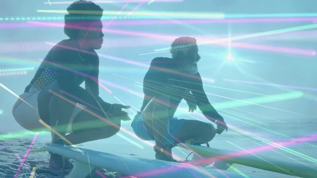 Man pointing sea spotting surfing wave, woman crouching preparing entry, light streaks over boards