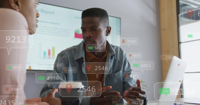 Woman speaking initiating overlaying data bubbles as man pointing at laptop reviewing annual charts