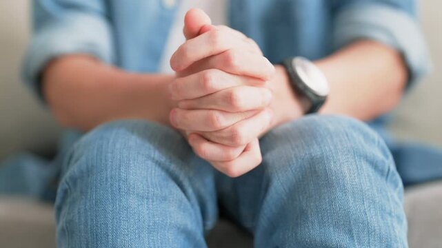 Closeup legs shaking in a guy in blue jeans. Uncontrollable leg shaking. Severe stress in a guy. A man is worried while sitting on a sofa. Health problems and sickness