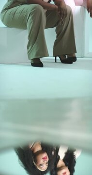 Vertical video: Camera dolling revealing diverse female colleagues posing on cube on glass panel