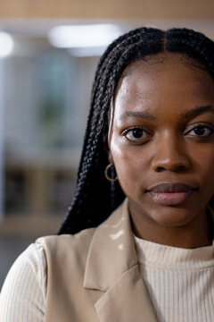 African American woman posing in office wearing gold hoop earrings beige blazer cream ribbed top