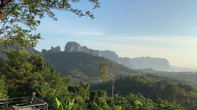 Warm sunrise light over green forest and limestone mountains at Din Daeng Doi in Krabi Thailand showing layered hills, clear sky, and peaceful tropical landscape