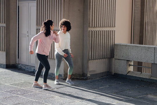 Diverse female friends walking briskly on paved plaza in leggings, sneakers, copy space