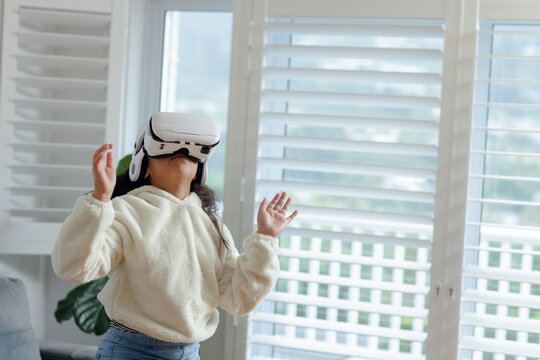 Virtual reality headset resting on fuzzy hoodie in simple living room with sofa cushions and plant