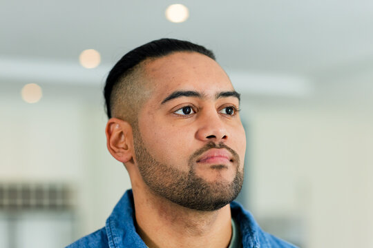 Bearded man standing at modern home kitchen wearing denim shirt and observing recessed lights