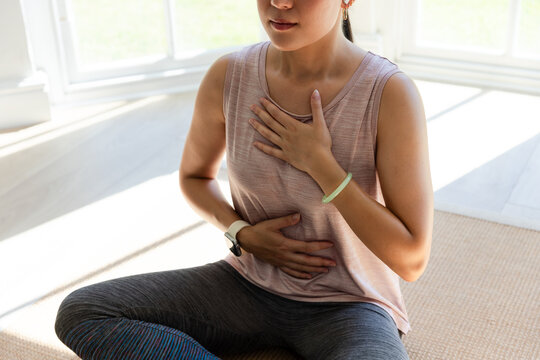 Woman sitting on mat following smartwatch prompt, breathing while animated pulse guiding wellness