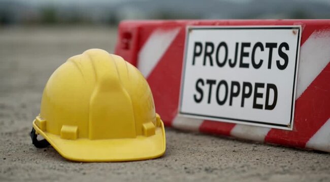 Construction site shutdown represented by a yellow hard hat and "Projects Stopped" sign