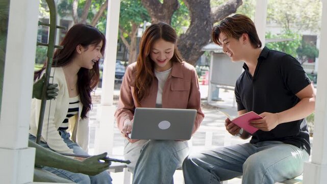 Three Asian University Students Studying Together with Laptop in Outdoor Gazebo