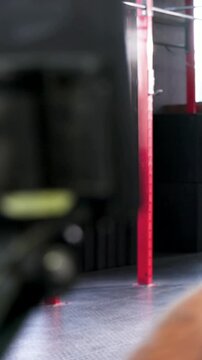 Vertical video: Rowing man wearing gray top pulling handle when timer starts at gym, rower visible