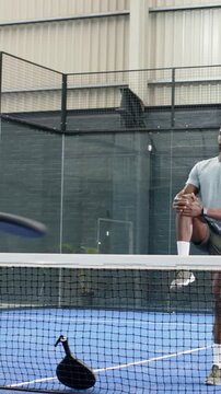Vertical video: Man in gray tee starting drill and doing backhand swings at court, with paddle