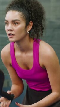 Vertical video: Standing athlete in tank gripping handle leaning forward on blue court awaiting cue
