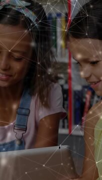 Vertical video: Two girls tapping and passing tablet, starting network while learning in library