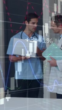 Vertical video: Glancing at laptop, MDs reviewing file, assessing animated finance charts over them