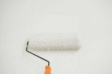 Obraz premium Roller Brush Painting, Worker painting on surface wall Painting apartment, renovating with white color paint. Leave empty copy space to write descriptive text beside. 