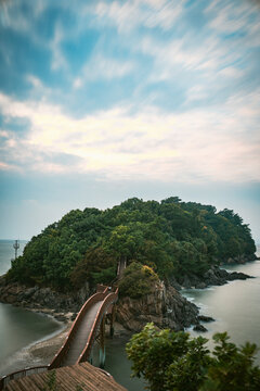 Scenic walkway connecting to a rocky island over the sea.