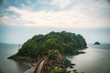 Wooden bridge leading to a lush green island in South Korea. © ABOUT PHOTOGRAPHY 