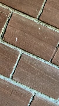 Cinematic push-in and circular pan of brown ceramic wall tiles. Dynamic close-up of outdoor masonry texture with diagonal grout lines.