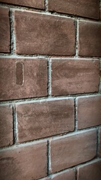 Close-up of red brick wall texture. Vertical pan of traditional masonry with weathered details.