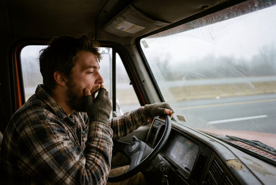 Tired truck driver yawning while driving on the road feeling sleepy and fatigued