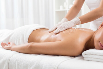 Obraz premium Beautician applying body scrub to woman back in spa salon