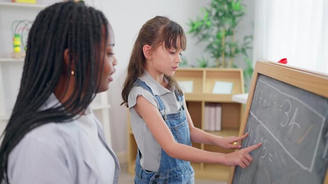 African woman tutor guide young child through learning activity in nursery.