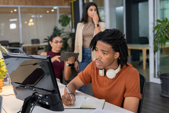 Diverse coworkers collaborating at modern open-plan office with tablet, notebook and pen
