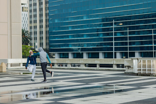 African american men stretching on rooftop wearing athletic wear by puddles