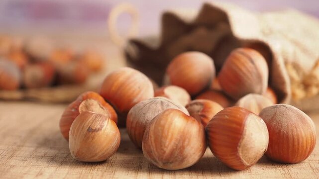 Close-up footage of organic hazelnuts spilling from a burlap sack onto a wooden surface