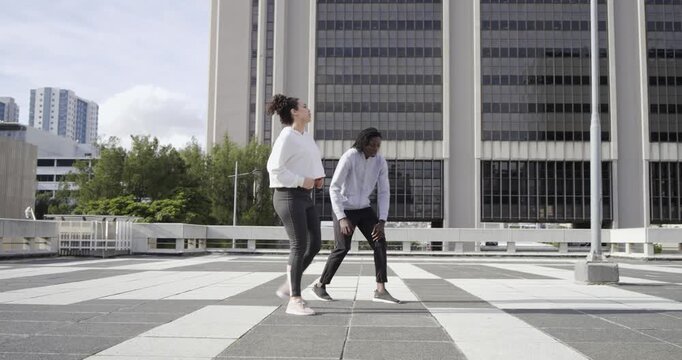 Starting rooftop workout, diverse friends jogging, checking trackers, high-fiving, stretching