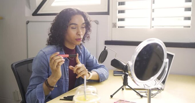 Starting tutorial non-binary creator greeting camera at studio showcasing lip gloss, filling brows