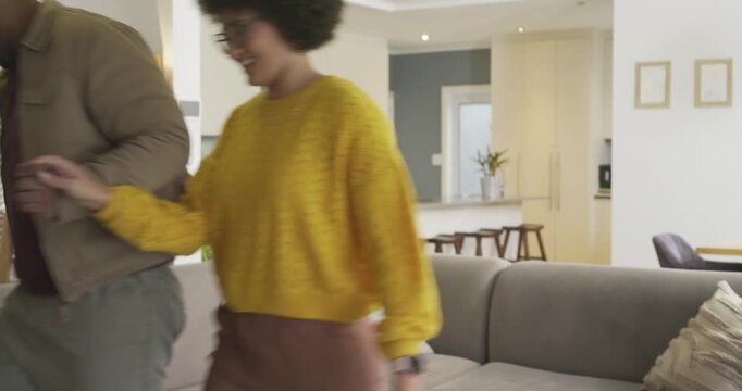Couple sharing whispered conversation on gray couch then rising and dancing by kitchen island