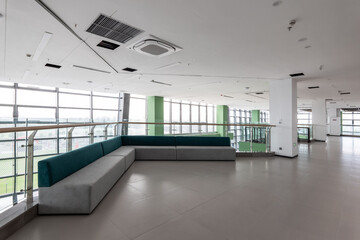Naklejka premium Modern office interior featuring green sofas in a spacious lounge area with large windows