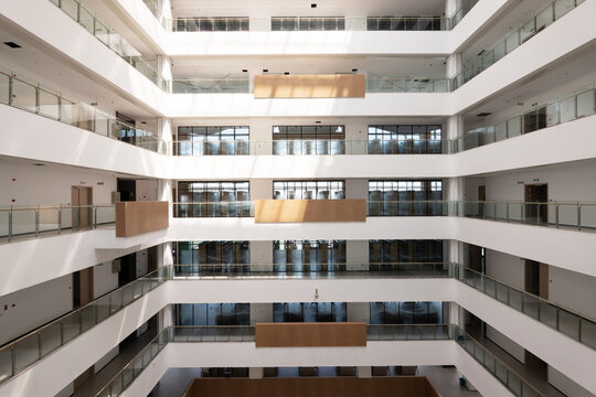 Modern multi-story office building atrium with glass railings and wooden accents