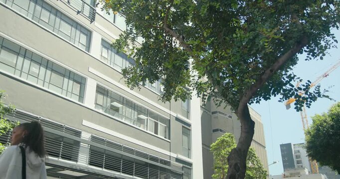 Diverse pedestrians walking on sidewalk past building, tree with yoga mat, basketball, copy space