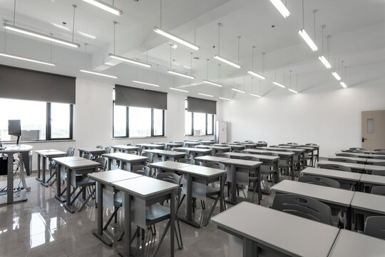 Spacious modern classroom with neatly arranged desks and chairs under bright overhead lighting