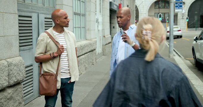 African American men standing on sidewalk with bags pointing outward with phone after woman passing