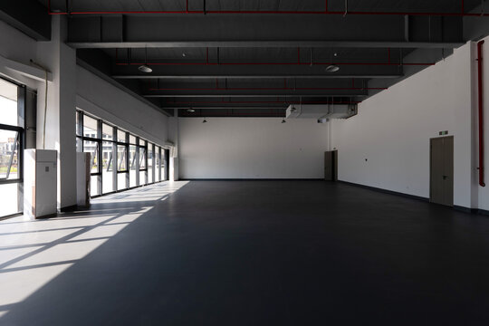 Spacious industrial-style factory interior with exposed ceiling pipes and large windows