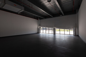Naklejka premium Spacious industrial-style factory interior with high ceiling and large roll-up doors