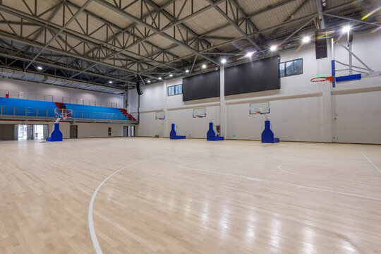 Indoor basketball gym with empty wooden court floor and modern structural design