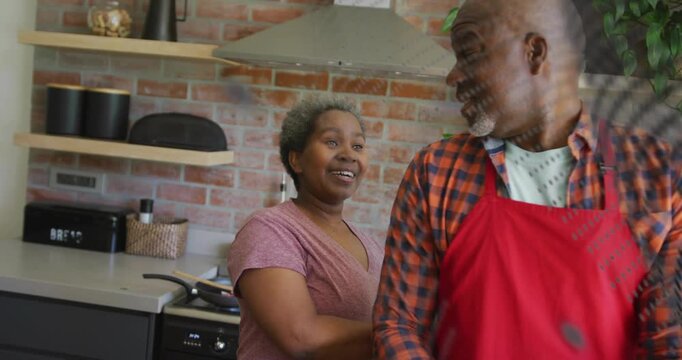 Vertical video: Glancing man leading woman reaching back at stove cooking with pan, apron, dots