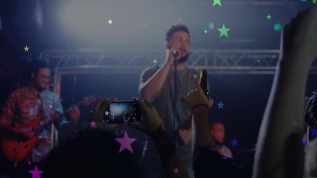 Singer singing onstage as crowd raising phones and filming music, star overlay popping over screens