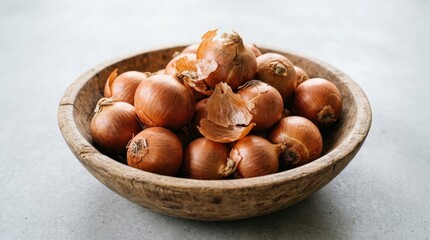 Obraz premium A rustic wooden bowl brimming with fresh brown onions, their papery skins hinting at savory culinary potential.