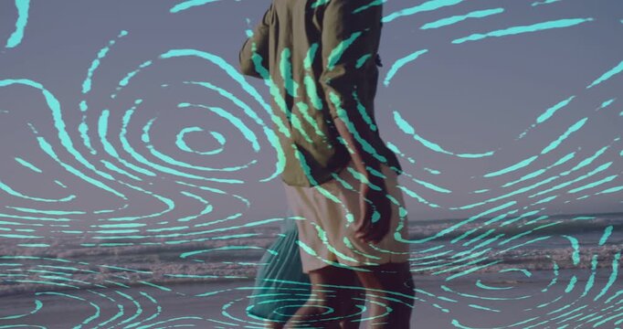 Vertical video: Walking family at beach, child in teal reaching up and adult lifting her, overlay