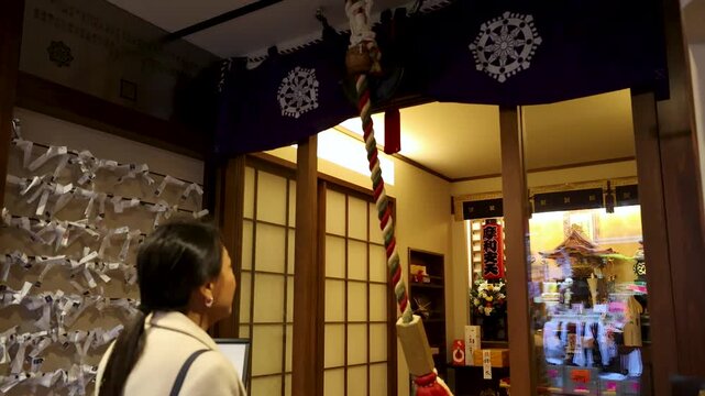 Japanese Woman Ringing Suzu Bell Rope at Shinto Shrine in Tokyo