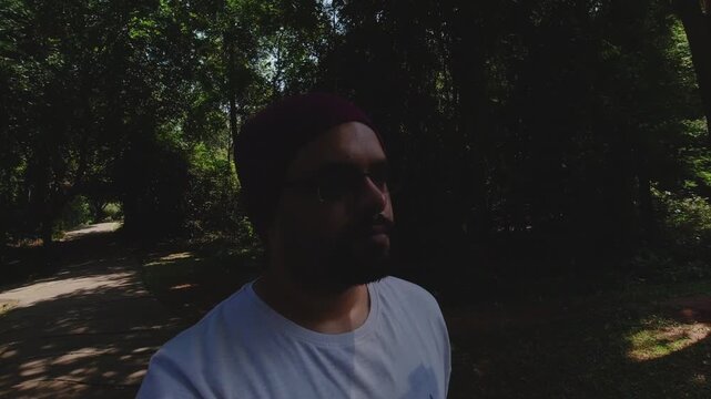 Indian Man walks through lush resort greenery in slow motion, afternoon serenity