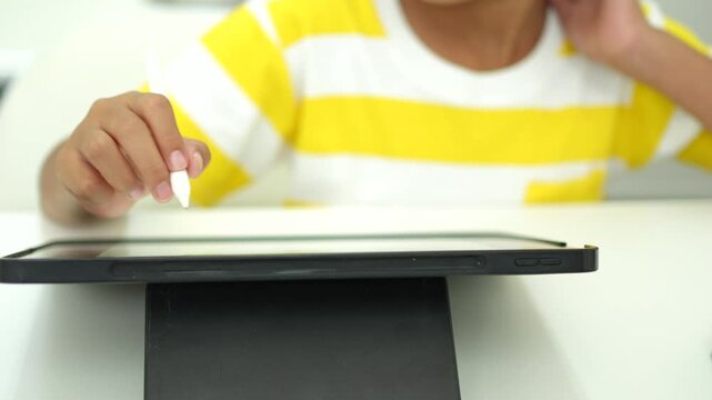 Child girl watching online tutorial and drawing digital pictures using digitized pen and digital tablet