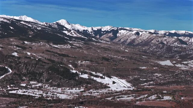 Buttermilk Ski resort Aspen ski town winter sunny blue sky bluebird morning aerial drone Colorado Aspen Snowmass town ski trail runs Maroon Bells Wilderness Aspen Airport backwards pan up motion